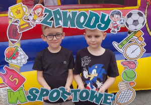Chłopcy ze Słoneczek pozują do zdjęcia w ramce.