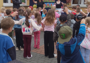 Przedszkolaki wykonują rogrzewkę zanim rozpoczną zabawy sportowe.