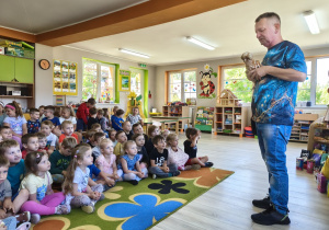 Wolontariusz trzyma w dłoniach kurę i opowiada o niej ciekawostki.