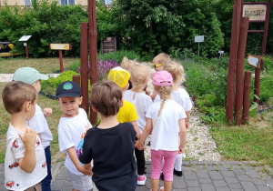 Dzieci ustawione w parach przechodzą pod bramą z napisem "Królestwo owadów".