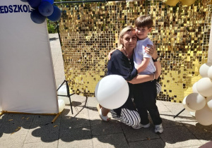Staś i Pani Monika pozują do wspólnego zdjęcia na tle złotej ścianki.