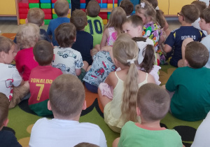 Pani policjantka stoi przy tablicy multimedialnej i opowiada o bezpieczeństwie podczas wakacji.