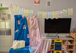 9. Kolorowy napis Dzień dziecka, a w tle niebiesko-różowa dekoracja i zapakowane upominki dla dzieci.