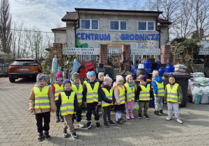 1. Dzieci z grupy "Motylki" stoją i pozują do zdjęcia na placu przed Centrum Ogrodniczym.
