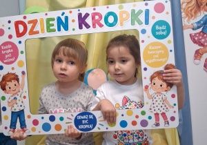 Dwie dziewczynki pozują do zdjęcia w fotoramce z okazji Dnia kropki.