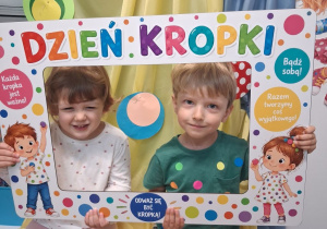Dziewczynka i chłopiec pozuje do zdjęcia w fotoramce z okazji Dnia kropki.