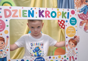 Chłopiec pozuje do zdjęcia w fotoramce z okazji Dnia kropki.