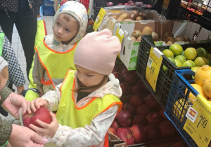 8. Dziewczynka wkłada jabłko do torebki trzymanej przez panią.