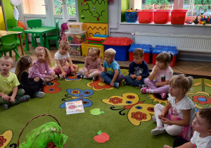 3. Dzieci siedzą w kole i oglądają różne odmiany jabłek.