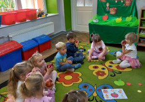 5. Dzieci siedzą w kole, trzymają w rączkach jabłka, które za chwilę zjedzą.