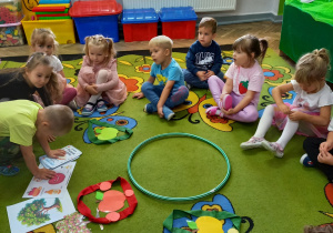 7. Dzieci siedzą na dywanie i układają zbiory jabłek.
