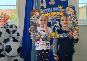 16. Chłopiec z dziewczynką pozują w ramce z napisem Dzień Chłopca.