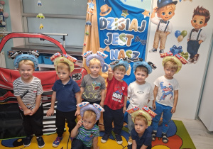 4. Zdjęcie grupowe chłopców na tle dekoracji w opaskach z samochodami.