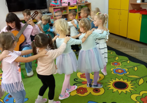 3. Dzieci tańczą w kółeczku, zaproszony gość gra na gitarze.