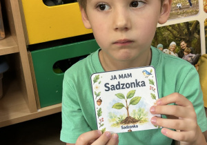 10.Chłopiec trzyma w rękach obrazek z sadzonką drzewa.