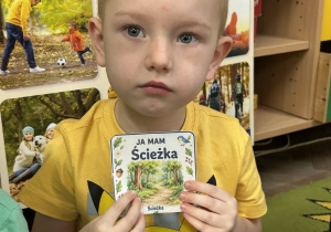 9. Chłopiec pokazuje kartę na której narysowana jest ścieżka w lesie.