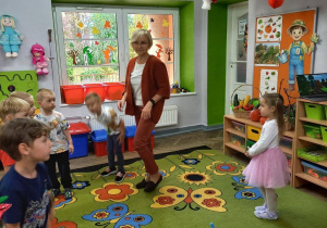 3.Dzieci z nauczycielką poruszają się w rytmie muzyki wokół żuczków śpiewając piosenkę Let s play – bawimy się.