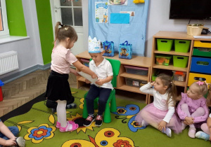 2. Dziewczynka wręcza solenizantowi drobny upominek i dyplom z okazji urodzin.