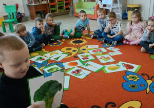 16. Chłopiec trzyma w ręku obrazek z brokułem.