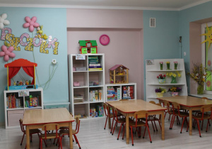 Sala grupy I "Pszczółki" - trzy stoły, kącik przyrody z wiosennymi kwiatami, szafki z układankami oraz kącik książki, na którym stoi teatrzyk. Na ścianie znajduje się napis "Pszczółki" i trzy lampki w kształcie stokrotek.