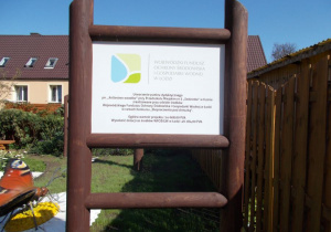 Tablica informacyjna zamontowana na drewnianym stelażu o dofinansowaniu projektu ze środków Wojewódzkiego Funduszu Ochrony Środowiska i Gospodarki Wodnej.