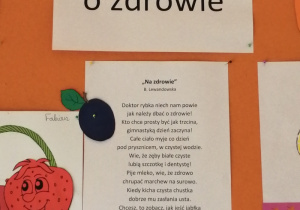 Na tablicy znajduje się napis "Dbam o zdrowie", przy którym umieszczona jest sylweta cebulki oraz wiersz pod tytułem "Na zdrowie". Obok wierszyka przypięta jest sylweta jabłka i śliwki.